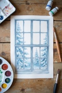 Watercolor painting of a snowy forest scene viewed through a window, with art supplies on a wooden table.