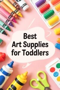 Colorful art supplies for toddlers on a pink surface, including crayons, paint, and scissors.