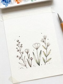 Minimalist floral illustration with delicate watercolor flowers on paper, next to a paint palette and pen.